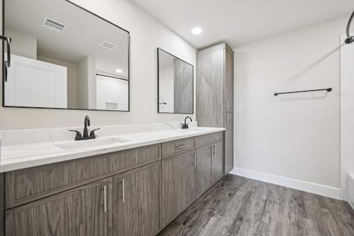 A bathroom with a double sink vanity and a walk-in shower.