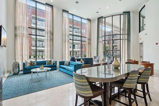 A modern living room with a glass table and blue chairs.