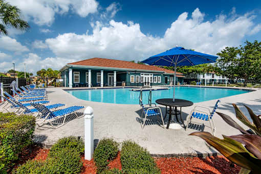 A pool area with a table and chairs and a building in the background.