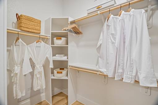 A white bathroom with towels and a basket on the shelf.