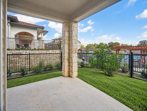 A porch with a black railing and a stone pillar.