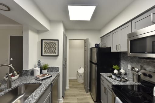 a kitchen with granite counter tops and a stainless steel refrigerator