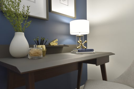 a desk with a lamp and a vase on it