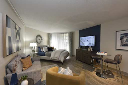A bedroom with a bed, a couch, a chair, and a television.