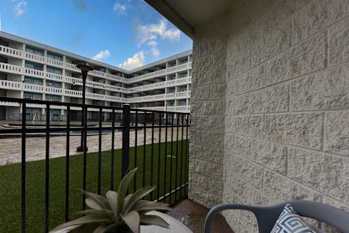 A balcony with a chair and a plant in front of a building.