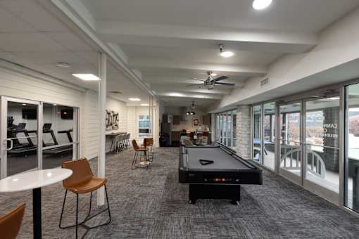 A room with a pool table and chairs.