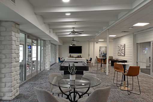 A modern dining room with a glass table surrounded by grey chairs.