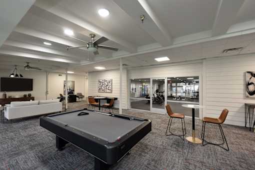A room with a pool table and a fan.