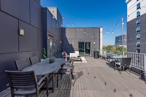 A wooden table and chairs are set up on a rooftop patio.
