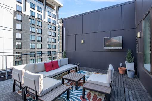 A balcony with a couch, chairs, and a table with a potted plant.