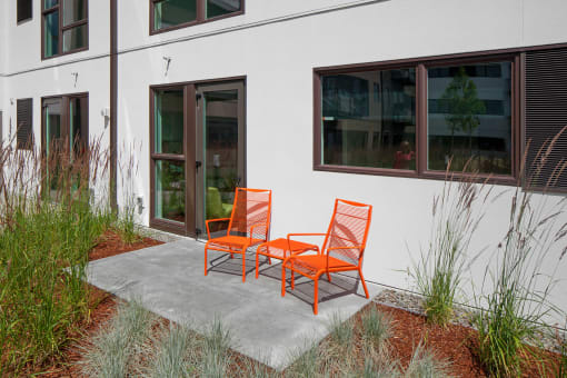 a pair of orange adirondack chairs sit on a concrete patio in front of a