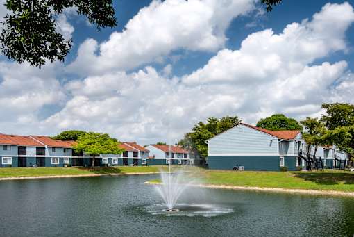 A fountain in the middle of a lake in front of a building.