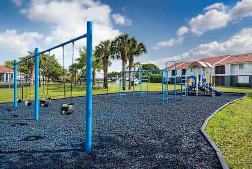 A playground with a blue swing set and a gravel ground.