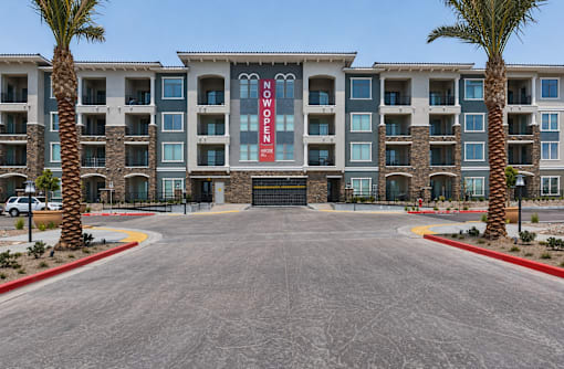 A large building with a red sign that says "NOW OPEN" is surrounded by palm trees.