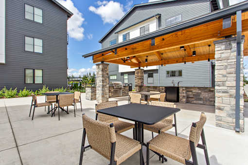 A patio with a table and chairs is in front of a house.