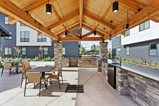 A patio with a table and chairs under a wooden roof.