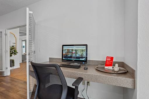 A black chair is in front of a desk with a computer and a mouse.