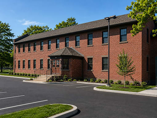 A red brick building with a black roof and a tree in front.