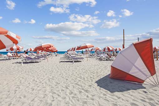 Modern Apartments in Downtown Miami 33139 for Rent – The Anamar at Collins Park – A beach scene with umbrellas and chairs.