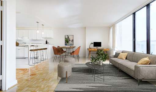 A modern living room with a grey sofa, wooden floors, and a kitchen area in the background.