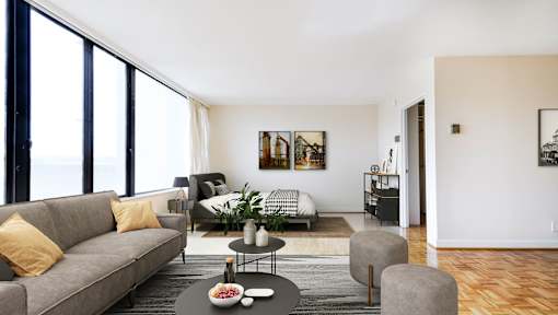 A living room with a grey couch, a coffee table, and a large window.