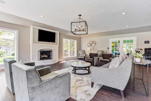 Apartments in Geneva, IL for Rent- Ashford at Geneva-  A modern living room with a grey sofa and a fireplace.