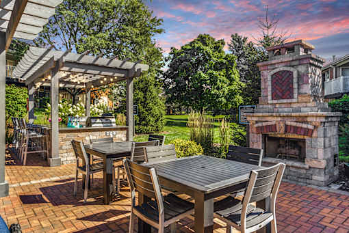 Apartments in Geneva, IL for Rent- Ashford at Geneva-  A patio with a table and chairs and a fireplace.