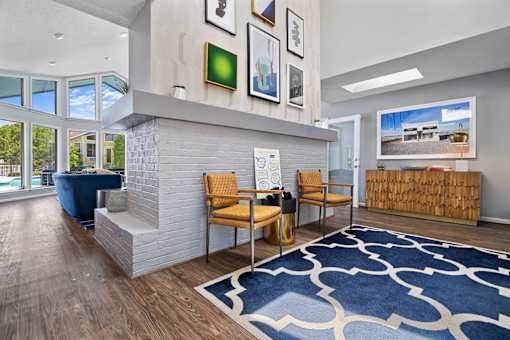 A living room with a blue rug and a white fireplace.