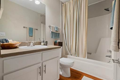 A bathroom with a white toilet, sink, and striped shower curtain.