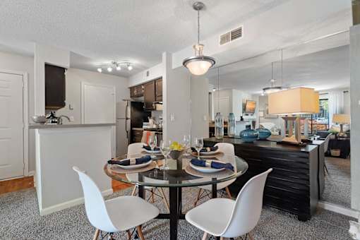 A modern dining room with a glass table and white chairs.