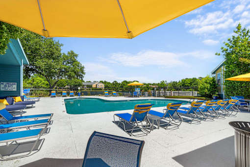 A pool area with sun loungers and a yellow canopy.