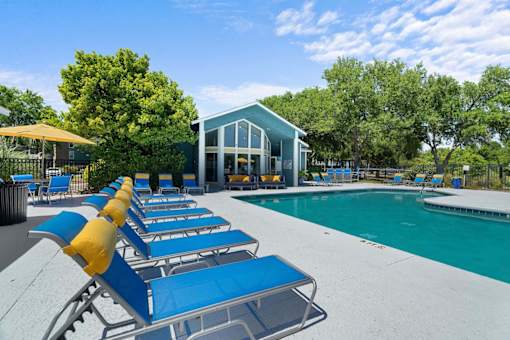 A poolside area with sun loungers and a building in the background.