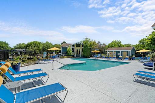 A pool area with sun loungers and a small building.