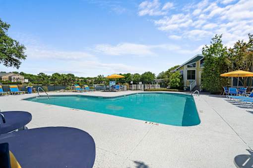 A large outdoor swimming pool with a blue tiled edge and a yellow umbrella.