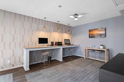 A room with a desk, chairs, and a ceiling fan.