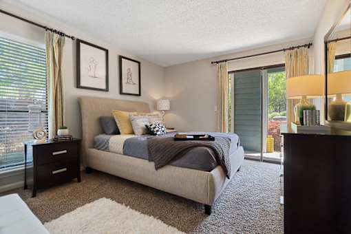 A bedroom with a bed, nightstand, and two framed pictures on the wall.