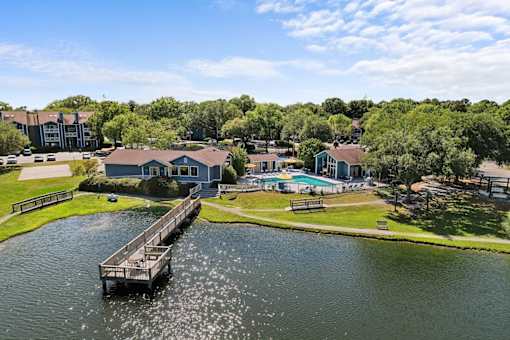 A dock extends into a body of water in front of a residential area.