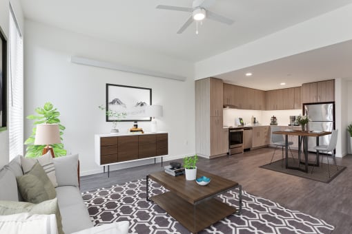 a living area with a couch coffee table and a kitchen in the background