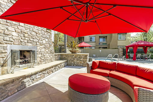 2-Bedroom Apartments in Sacramento, CA - Avanti - Outdoor Fireplace with Couch, Umbrella, and Cobblestone Bench