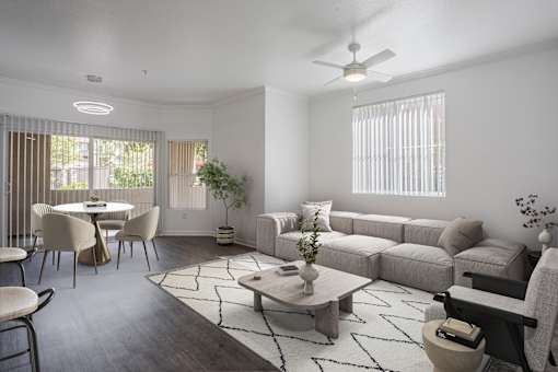 A living room with a grey sofa, a coffee table, and a dining table with chairs.
