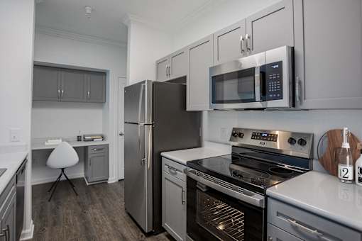 A modern kitchen with a stainless steel refrigerator, microwave, and oven.