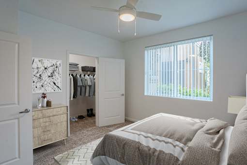 A bedroom with a large bed and a closet with clothes hanging.