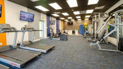 Newly Renovated Apartments in Mesa, AZ - Mesa Station Apartments - Fitness Center With Treadmills, Exercise Bikes, Strength Equipment, Wall-Mounted Televisions, And Bright Overhead Lighting.