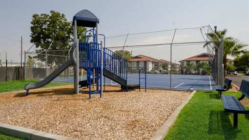Mesa, AZ, Apartments for Rent - Mesa Station - Playground with Slides, Wood-Chips, Benches, Surrounded by Grass.