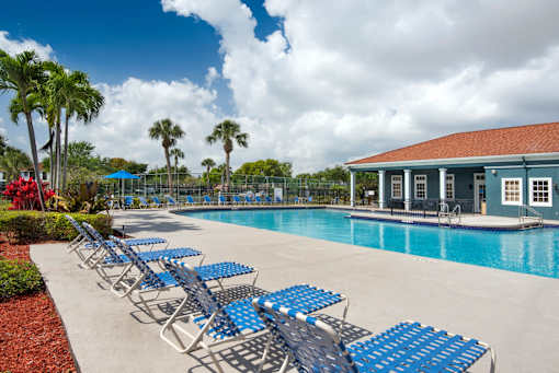 A poolside area with blue lounge chairs and a building in the background.