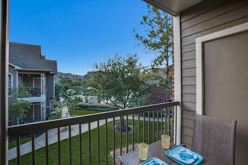 a balcony with a table and chairs overlooking a yard and houses