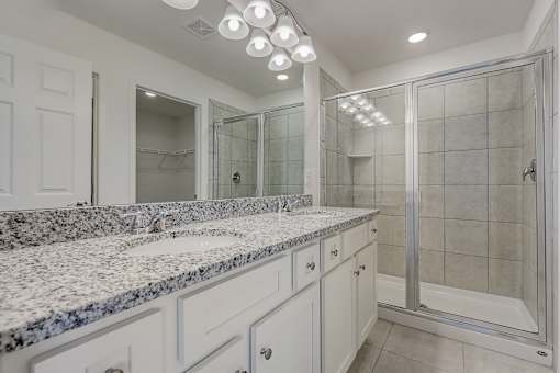 A bathroom with granite countertops and a walk-in shower.
