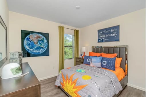 A bedroom with a bed, a dresser, and a painting of the Earth on the wall.