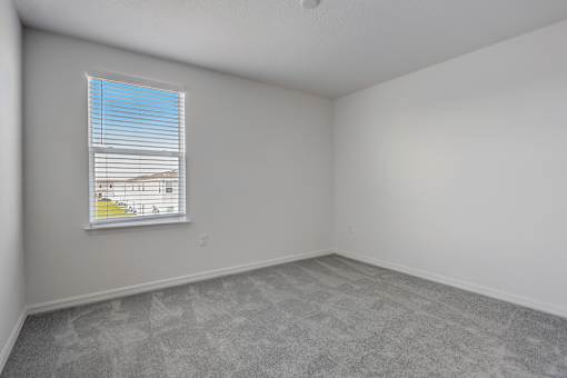 A room with a window and a carpeted floor.