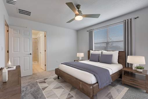 A bedroom with a bed, nightstands, and a ceiling fan.